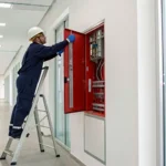 Technician providing fire alarm installation services for a commercial system control panel.